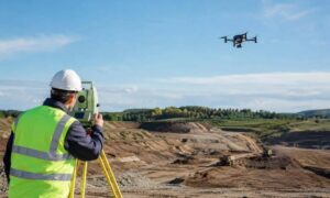 Land surveyor using a total station while a drone maps a construction site in kansas city kansas